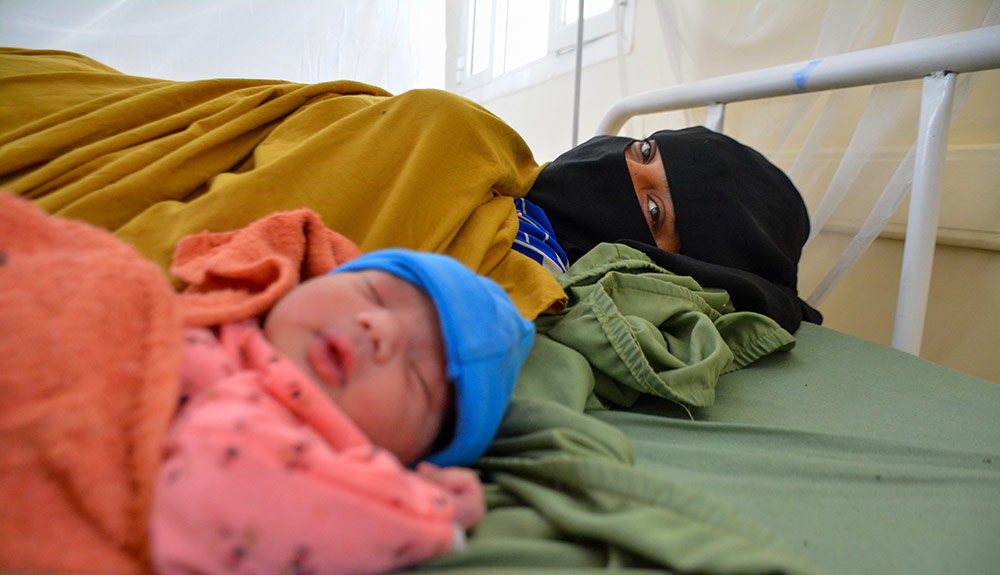 Zaima Hussain ligger i sängen med sin nyfödda Aiesha på sjukhuset i al-Qanawis, Jemen.