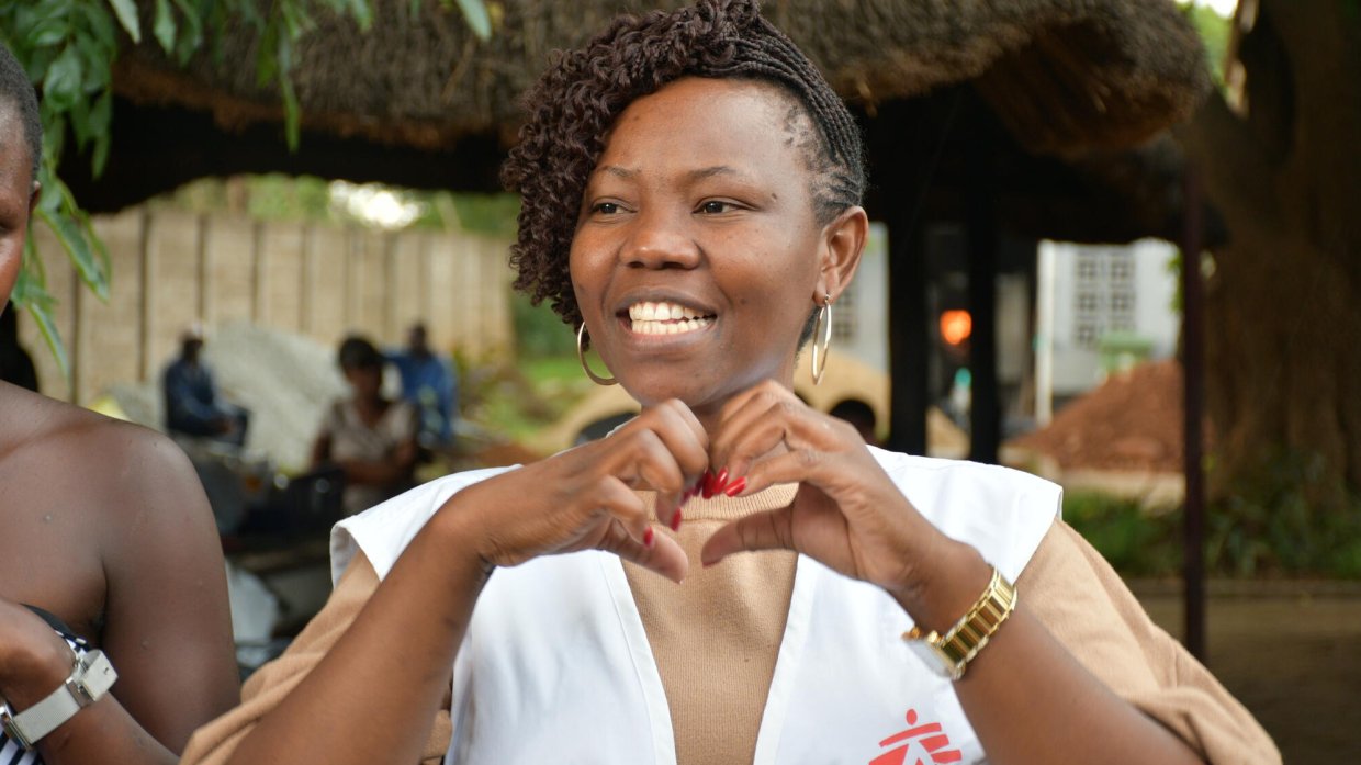 En glad person i Läkare Utan Gränsers väst gör hjärtsymbol med händerna.
