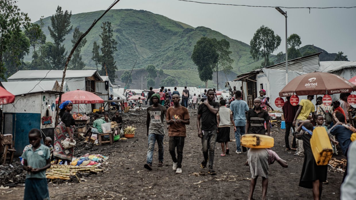 Människor på en marknad framför höga berg.