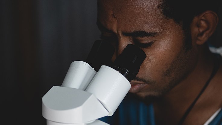 En man tittar i ett mikroskop