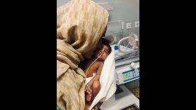 en förtidigt född bebis med syrgasslang i näsan hålls av sin mamma på neonatalintensiven 