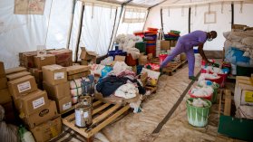 Tält fyllt av lådor och hinkar. Längre bak ser man blåklädd anställd som lutar sig ner i en av lådorna.