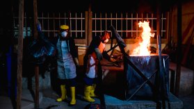 Städpersonal lägger i saker i tunna som brinner.