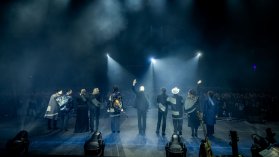 Artister på en scen fotade bakifrån medan de tackar publiken