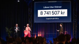 En kvinna tar emot en gåva från två män på en scen under en gala