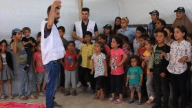 Man i MSF-väst håller händerna över huvudet inför hänförda barn