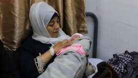 Kvinna tittar på nyfött barn i famnen