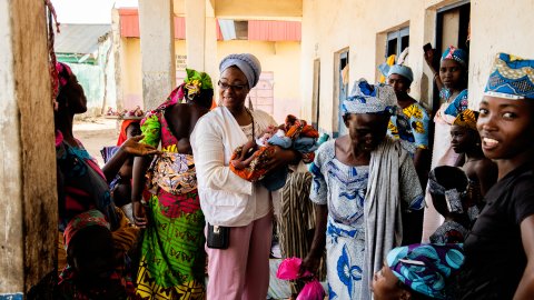 Suraiya håller i ett barn framför en massa kvinnor
