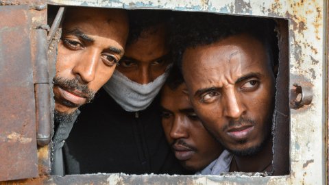 Fyra män tittar ut från ett förvar i Libyen.