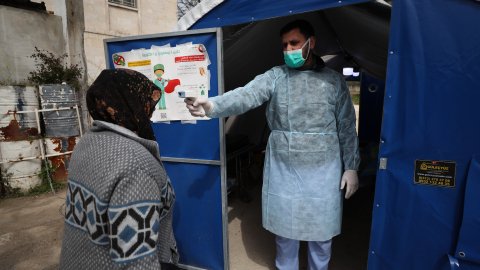 En man håller en termometer mot pannan på en kvinna