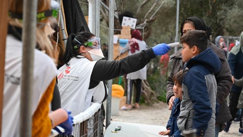 Medicinsk personal tar temperaturen på ett barn i flyktinglägret Moria, på den grekiska ön Lesbos.
