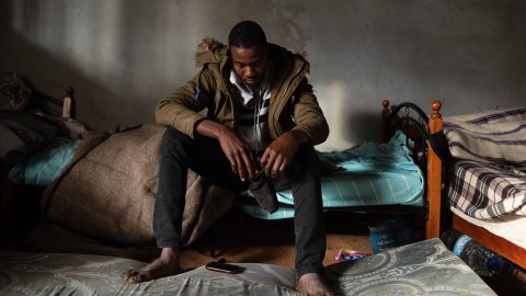 En man sitter på en säng med sänkt huvud.