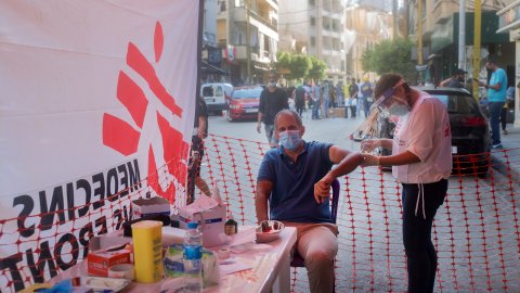 En man sitter på en stol och får vård vid en mobil klinik efter explosionen i Beirut, Libanon.