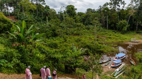 Personal påväg till båtar för transport i Amazonas regnskog