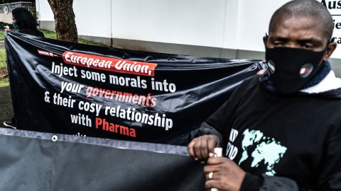 En man står vid ett plakat vid en demonstration för rättvis fördelning av covidvaccin i Sydafrika.