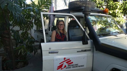 Sjuksköterskan Ulli Hedberg, som är i Haiti, står bakom en bildörr och tittar in i kameran.