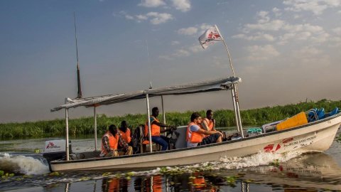 En ambulansbåt med vår flagga på taket åker snabbt genom ett översvämmat område.