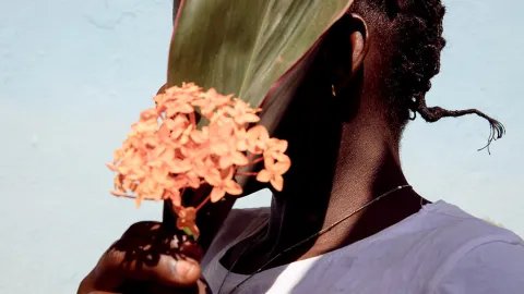 En kvinna i Centralafrikanska republiken håller en blomma framför sitt ansikte.