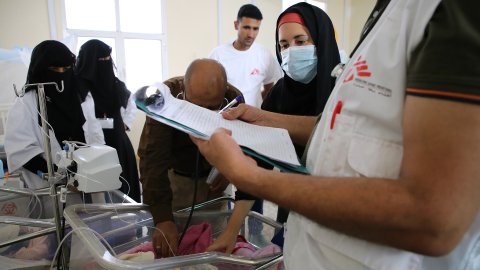 Personal undersöker en bebis under en rond på sjukhuset i al-Qanawis.