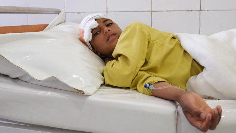 Ett barn som fått vård för en skottskada i huvudet vilar på en sjukhussäng.