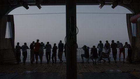 Flera människor står i motljus på däck ombord på sök- och räddningsfartyget Geo Barents och tittar ut mot havet.