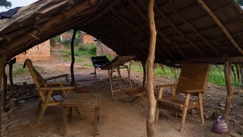Två övergivna stolar och en gammal brits under en halmtak i Nzako, Centralafrikanska republiken.