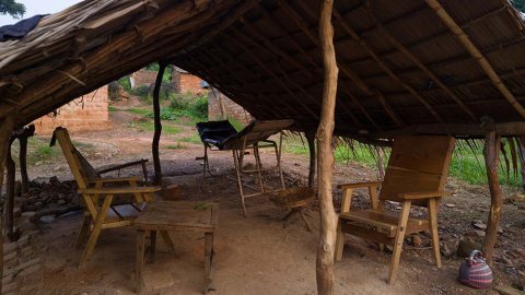 Två övergivna stolar och en gammal brits under en halmtak i Nzako, Centralafrikanska republiken.