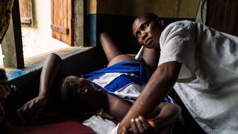 Octavia Braza, som bor i Nzacko, Centralafrikanska republiken, ligger på en brits i färd med att föda sitt sjunde barn. Barnmorskan Sylvia lyssnar på bebisens hjärtslag.