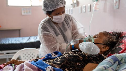 Sjukvårdspersonal hjälper 109-åriga Bonifácia de Oliveira med andningen. Bonifácia ligger i en säng där hon vårdas för covid-19 på ett sjukhus i Brasilien där Läkare Utan Gränser jobbar för att stötta covidinsatsen i Amazonasregionen