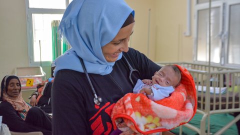 Barnläkaren Mónica Costeira, som arbetar på vårt sjukhus i al-Qanawis, Jemen, håller en liten bebis i famnen och ler.