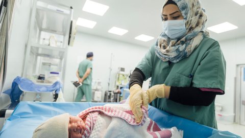 En nyfödd bebis på Nablus sjukhus i västa Mosul, Irak, sveps in i en filt av en sjukvårdspersonal.