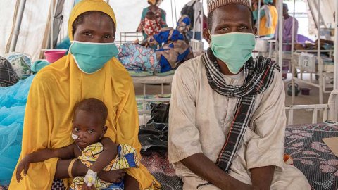 Ali, som vårdas på sjukhuset  i Magaria i Niger för malaria och uttorkning, sitter i sin mammas knä på en säng.