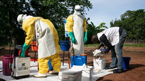 Teamledaren Gilkenny Okonkwo i delstaten Ebonyi i sydöstra Nigeria ser till att skyddsutrustningen sitter som den ska på två kollegor inför saneringen av ett hus där lassaviruset upptäckts.
