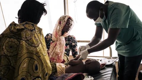 Ettåriga Mercian ligger på en brits på en vårdinrättning i Kongo-Kinshasa. Hon undersöks av en medarbetare från Läkare Utan Gränser för feber, diarré och hosta på 