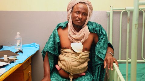 Mahamadou Agaïri bär sin två dagar gamla bebis hud mot hud på sjukhuset i Ansongo, Mali, medan mamman återhämtar sig från en svår förlossning.