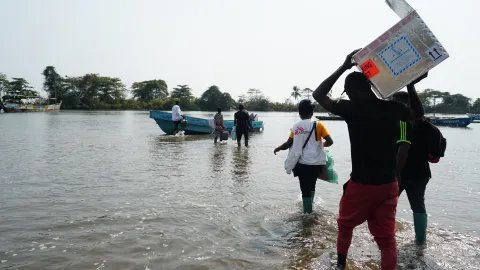 Ett team från Läkare Utan Gränser vadar ut till en båt efter att ha vaccinerat 419 personer mot kolera i byn Enyenge, sydvästra Kamerun.