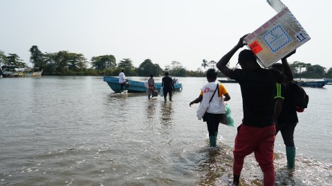 Ett team från Läkare Utan Gränser vadar ut till en båt efter att ha vaccinerat 419 personer mot kolera i byn Enyenge, sydvästra Kamerun.