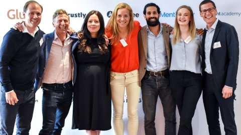 Sju anställda på Alfén och Didrikson står mot en vägg och håller varann om axlarna