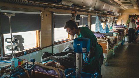 Sjuksköterskan Dmytro Mohylnytskyi tittar till en patient ombord på Läkare Utan Gränsers medicinska tåg i Ukraina.