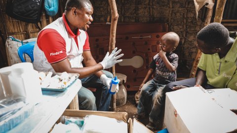 En sjuksköterska pratar med ett ungt barn som har sin pappa bredvid sig. 