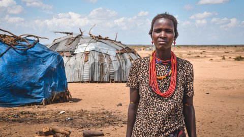 En kvinna står framför det som brukade vara familjens hydda. 