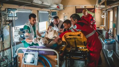 I en tågvagn flyttar Läkare Utan Gränsers personal en patient från en bår till en säng.
