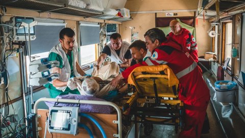 I en tågvagn flyttar Läkare Utan Gränsers personal en patient från en bår till en säng.