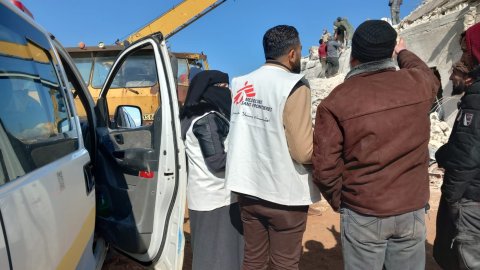 Två personer med Läkare Utan Gränser västar står och kollar på rasmassorna efter jordskalvet som drabbade Syrien och Turkiet.