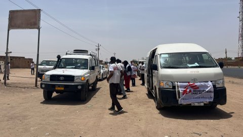 Bland några bilar står en grupp människor och pratar. 