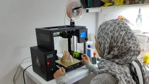 En kvinna sitter framför en 3D-skrivare.