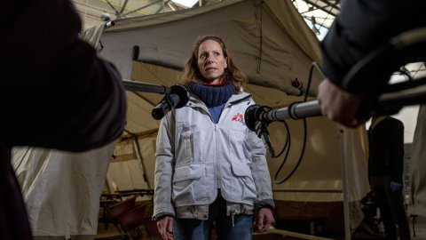 Kvinna i Läkare Utan Gränser-kläder blir intervjuad med två mikrofoner riktad mot sig.