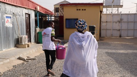 En medarbetare leder en kvinna och hennes barn ut från kliniken.