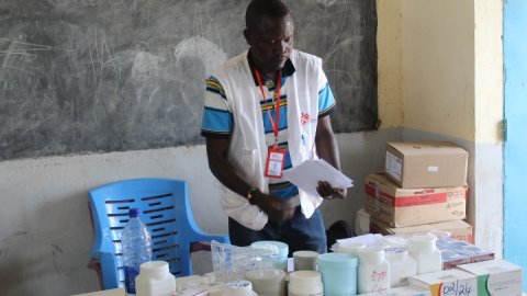 en man ställer upp askar med mediciner på ett bord i en vårdmottagning