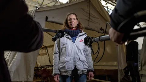En anställd på Läkare Utan Gränser blir intervjuad av TV framför ett sjukvårdstält